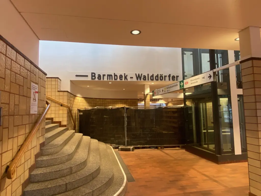 Bauzaun in der Eingangshalle während der Bauarbeiten, mit Wegweisern und Glasaufzug