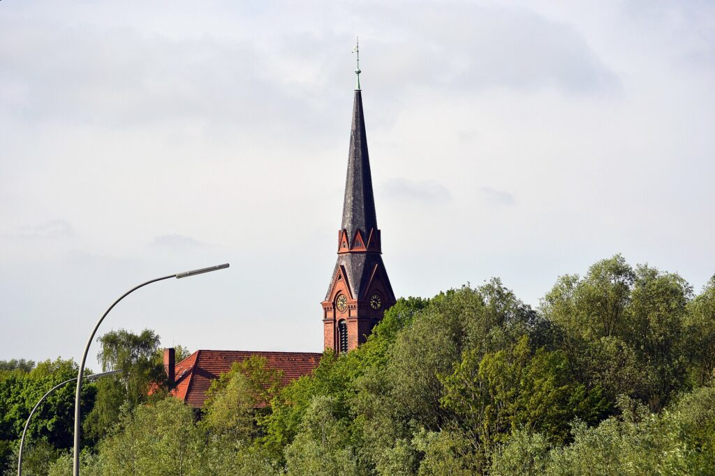 Der Backsteinturm der Kirche St. Gertrud in Hamburg-Altenwerder ragt über dichte Baumkronen