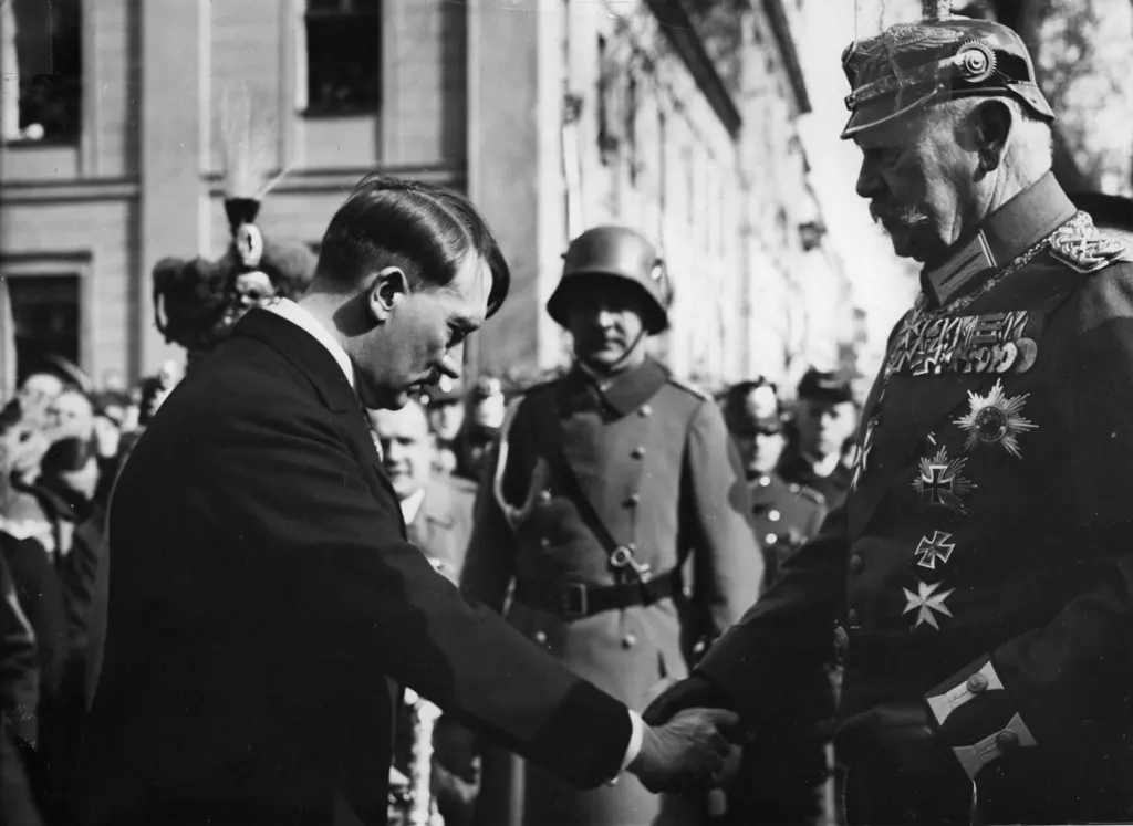 Reichspräsident Paul von Hindenburg im Feldmarschallsmantel schüttelt Reichskanzler Adolf Hitler vor der Potsdamer Garnisonkirche die Hand, 21. März 1933