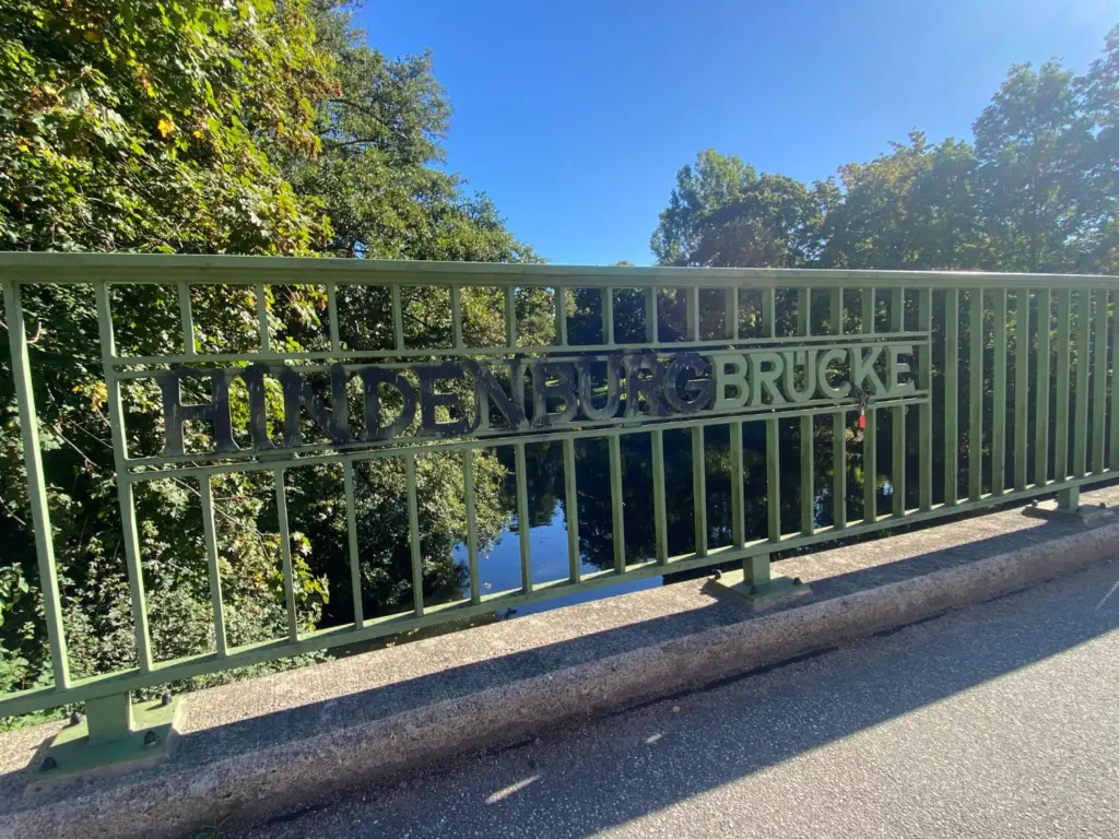 Metallschriftzug HINDENBURGBRÜCKE am Geländer der heutigen Traute-Lafrenz-Brücke; HINDENBURG ist schwarz übersprüht, BRÜCKE zeigt die unveränderte Originalpatina